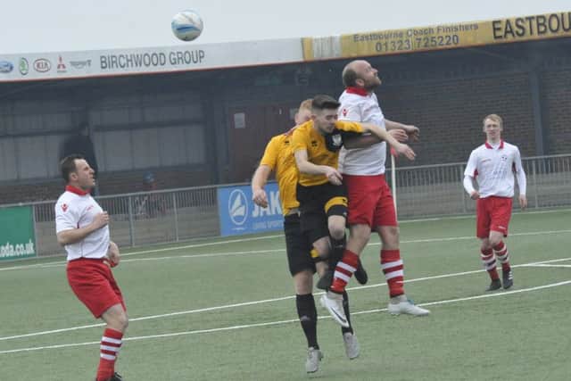 Bexhill United midfielder Kyle Holden challenges Langney Wanderers forward Shane Saunders for an aerial ball.