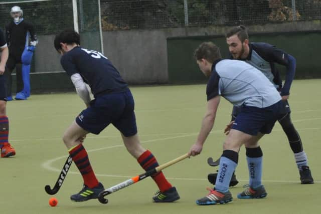 A Kings & Alleyns player turns away from South Saxons duo Will Orr and Alex Coombs.