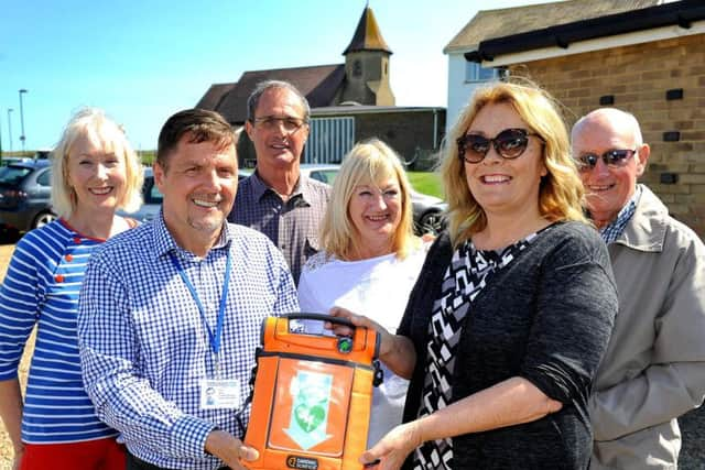 Councillor Joss Loader receives the devices from Terry Ayres, chief executive officer at Sussex Heart Charity