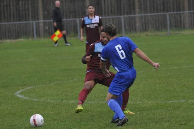 Broadbridge Heath midfielder Tom Howard-Bold slides the ball past the outstretched leg of Little Common midfielder Wes Tate.