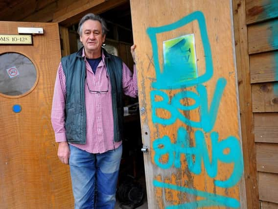 Bobby Schuck next to the Bev Gang graffiti tag left after the break-in. Photo by Steve Robards