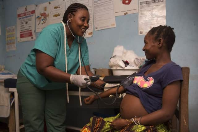 Heavily pregnant Jebbeh Konneh is checked by Nurse Judith in a temporary clinic in Sawula village, Sierra Leone. This clinic, which receives support from Christian Aid, has no electricity and only two delivery beds.