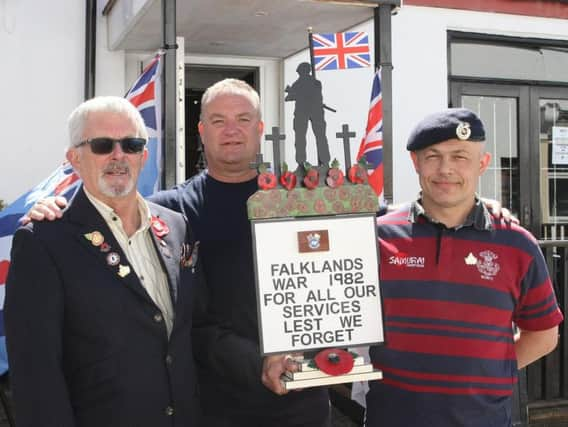 Wooden soldier statue made by Men in Sheds donated to Veterans Clubin Littlehampton and ending up at a church in the Falklands. Roy Amos presents it to Ian Neville, accomapanied by Cllr Ian Buckland. Photo by Derek Martin Photography.