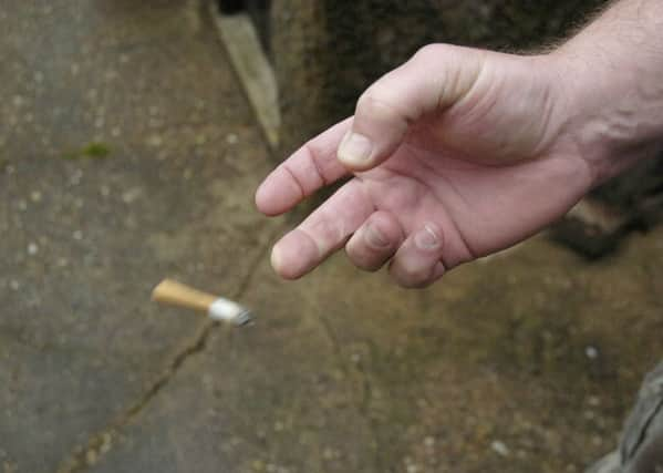 Hand flicking a cigarette butt on the floor. ENGEMN00120110628135420