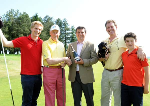 David Winch. pictured with three other generations of his family, receives a bottle of champagne from Golf at Goodwood general manager Stuart Gillett  Picture by Kate Shemilt C130757-3