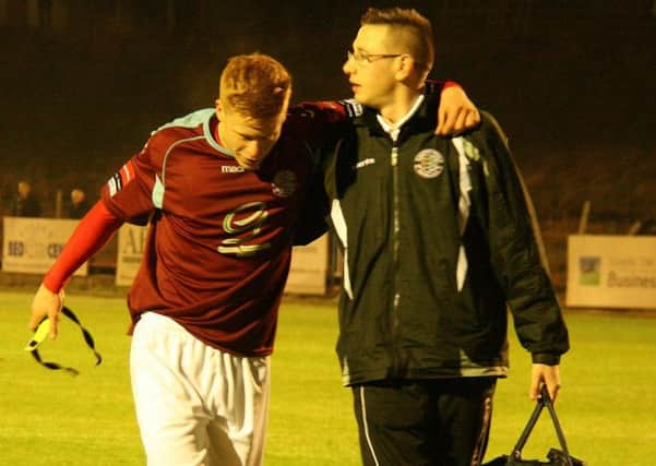 Hastings United striker Trevor McCreadie is helped off by physio Dane Martin in the 1-0 win over Herne Bay on Monday night. Picture by Terry S. Blackman