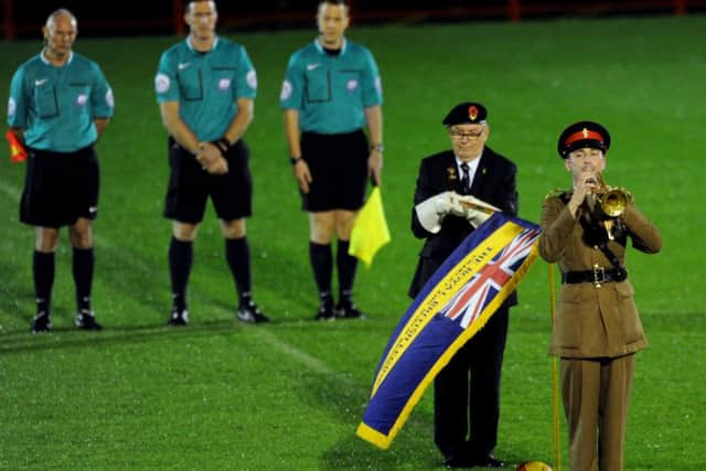 The last post is played by a serviceman prior to everyone present at Crawley Town's match against Gillingham observing a minutes silence before kick off on armistice day (Pic by Jon Rigby) SUS-141211-000530002