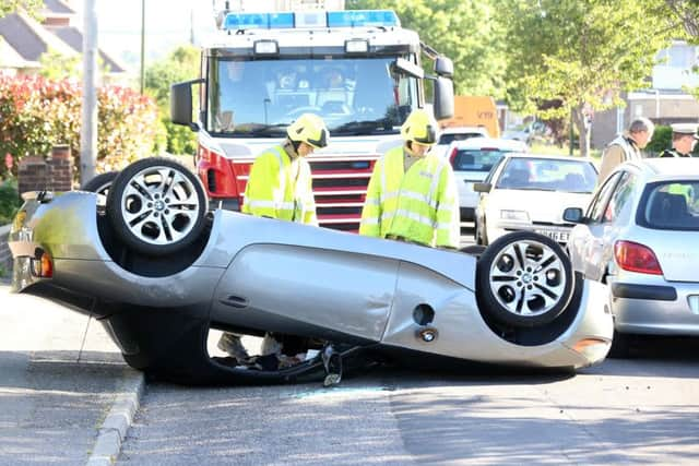 Firefighters inspect the car which flipped and landed on its roof