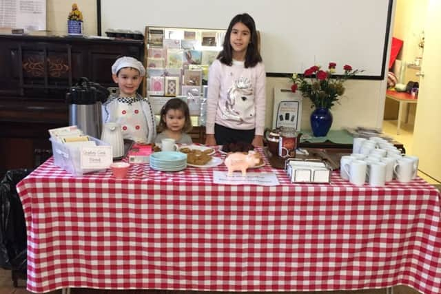 Isla, eight, Sidney, five, and Darcy, two, serving up cakes to the visitors