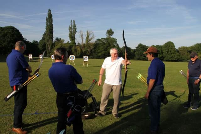 Paralympic archer Rob Anderson helps Leaping Hart Archery members with their release techniques