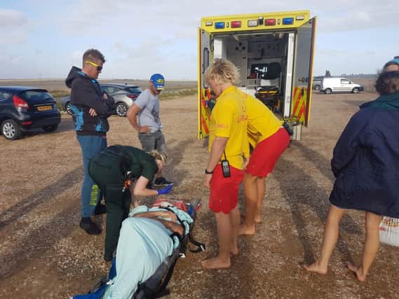 RNLI lifeguards Brett Wood (nearest to camera) and Leon Driver stay with the casualty until he is taken to hospital. Photo: RNLI SUS-170708-114718001