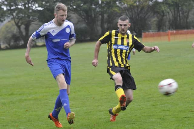 A Magham Down player clears the ball under pressure from a Catsfield opponent.