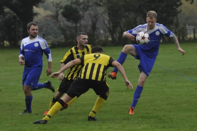 A Magham Down player tries to bring the ball under control with two Catsfield opponents in close attendance.