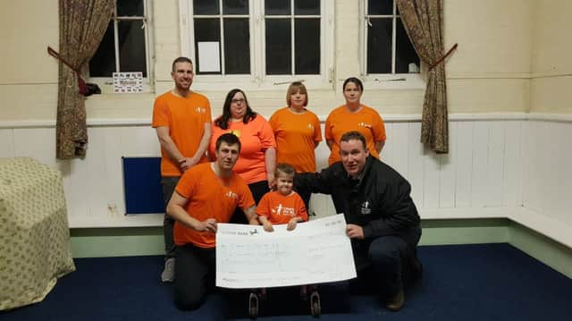 Summer Finlay (centre) with her dad Shaun hand over the cheque